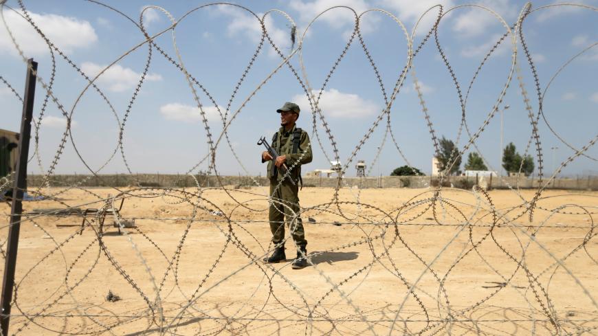A member of the Palestinian security forces, loyal to Hamas, stands guard as men set up a barbed wire on the border with Egypt, in Rafah in the southern Gaza Strip, August 24, 2017. REUTERS/Ibraheem Abu Mustafa - RC1F1E073D70
