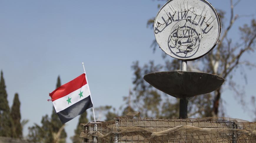 A Syrian national flag flutters next to the Islamic State's slogan at a roundabout where executions were carried out by ISIS militants in the city of Palmyra, in Homs Governorate, Syria April 1, 2016. REUTERS/Omar Sanadiki SEARCH "PALMYRA SANADIKI" FOR THIS STORY. SEARCH "THE WIDER IMAGE" FOR ALL STORIES - GF10000368423