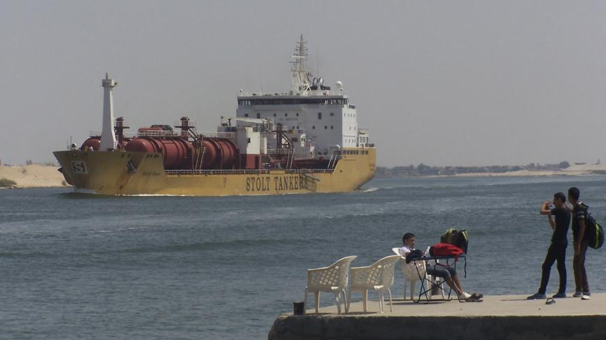 People are seen near a ship crossing  the Suez Canal near Ismailia port city, 120 km (75 miles) northeast of Cairo, June 13, 2013. A plan by Egypt's Islamist-led government to develop the land along the Suez Canal faces fierce opposition in districts that have been flashpoints for violence before, and may even threaten traffic on the strategic waterway. REUTERS/Stringer  (EGYPT - Tags: POLITICS) - GM1E96E0CMG01