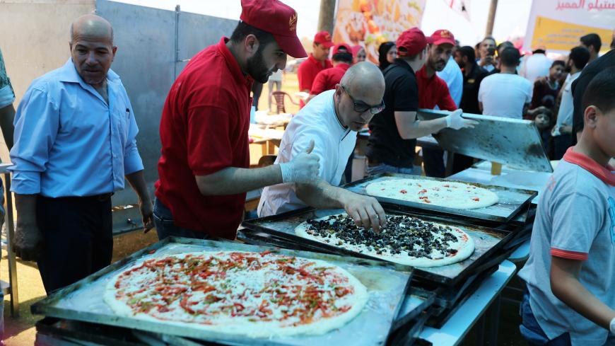An Italian chef (3rd L) prepares pizza for Palestinians during a food and cultural exchange event at the seaport of Gaza City June 1, 2016. REUTERS/Ibraheem Abu Mustafa  - S1BETHKKTPAA