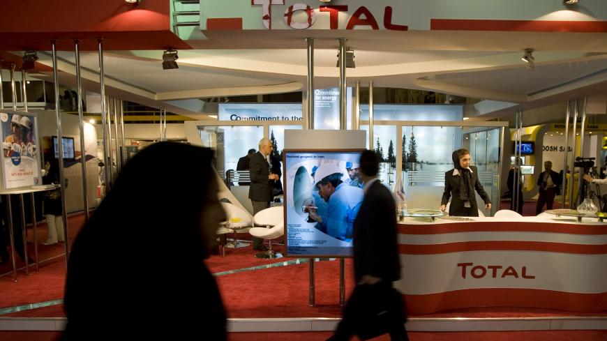 Visitors walk past Total's stand at the 14th International Oil, Gas & Petrochemical Exhibition (IOGPE) in Tehran April 21, 2009. REUTERS/Morteza Nikoubazl (IRAN BUSINESS ENERGY) - GM1E54L1IS801