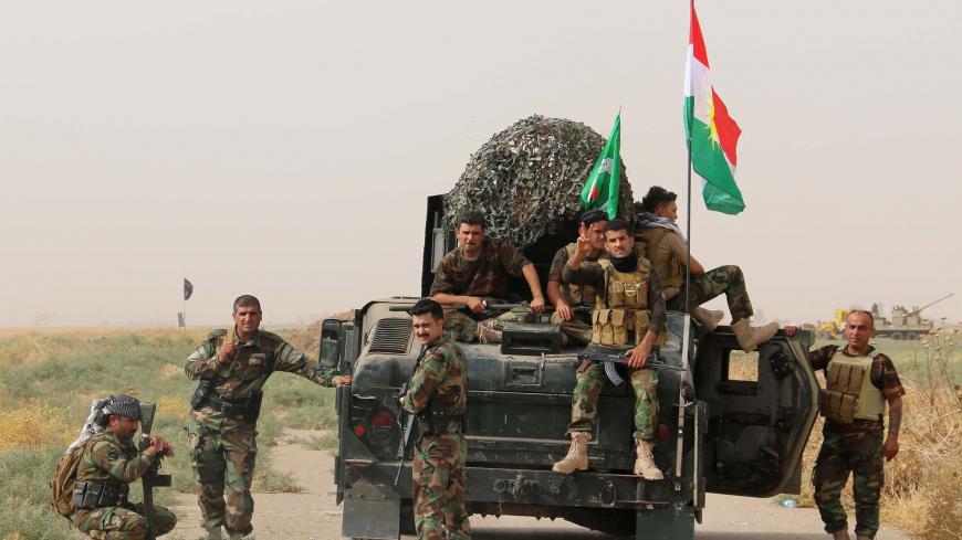 Iraqi Kurdish Peshmerga fighters pose for a photo next to a military vehicle bearing the Kurdish flag after they reportedly captured several villages from Islamic State (IS) group jihadistst in the district of Daquq, south of the northern city of Kirkuk on September 11, 2015. An Iraqi officer said that the operation was launched in the morning with support from international coalition aircraft, and has succeeded in retaking ten villages from IS. AFP PHOTO / MARWAN IBRAHIM        (Photo credit should read MA