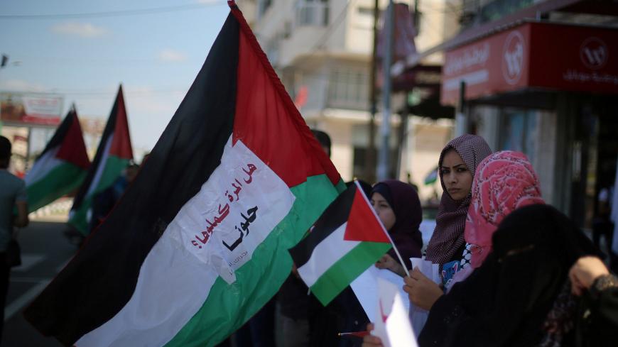 Women hold Palestinian flags as they celebrate after rival Palestinian factions Hamas and Fatah signed a reconciliation deal, in the central Gaza Strip October 12, 2017. Picture taken October 12, 2017. REUTERS/Ibraheem Abu Mustafa - RC1BDE142150