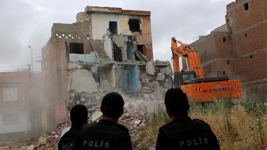 An excavator wrecks a building as part of an urban transformation project as police officers look on in Sur neighborhood in the Kurdish-dominated southeastern city of Diyarbakir, Turkey, May 23, 2017. REUTERS/Sertac Kayar - RC1846086EB0