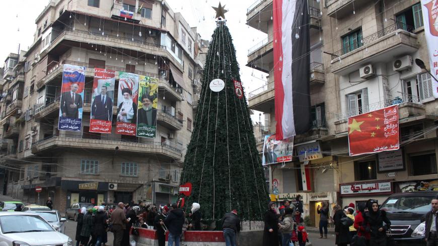 Syrians gather around a Christmas tree in Aleppo's government controlled Aziziyah neighbourhood on December 31, 2016.  / AFP / George OURFALIAN        (Photo credit should read GEORGE OURFALIAN/AFP/Getty Images)