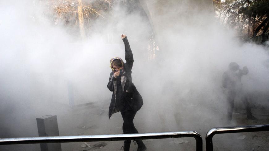 TOPSHOT - An Iranian woman raises her fist amid the smoke of tear gas at the University of Tehran during a protest driven by anger over economic problems, in the capital Tehran on December 30, 2017.
Students protested in a third day of demonstrations sparked by anger over Iran's economic problems, videos on social media showed, but were outnumbered by counter-demonstrators. / AFP PHOTO / STR        (Photo credit should read STR/AFP/Getty Images)