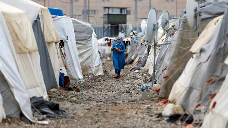 A Syrian refugee woman walks between tents in Nizip refugee camp, near the Turkish-Syrian border in Gaziantep province, Turkey, November 30, 2016. REUTERS/Umit Bektas - RC1B34636AE0