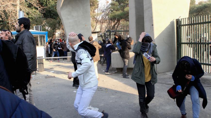 Iranian students run for cover from tear gas at the University of Tehran during a demonstration driven by anger over economic problems, in the capital Tehran on December 30, 2017. 
Students protested in a third day of demonstrations, videos on social media showed, but were outnumbered by counter-demonstrators.  / AFP PHOTO / STR        (Photo credit should read STR/AFP/Getty Images)
