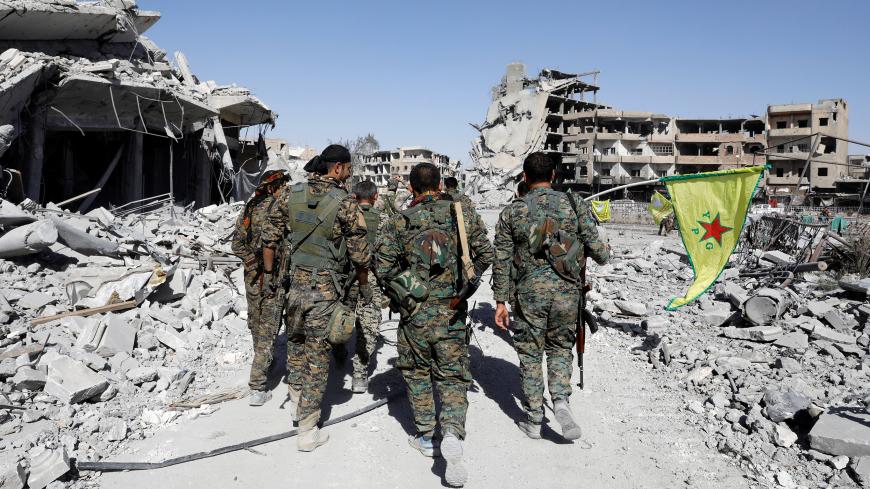Fighters of Syrian Democratic Forces walk past the ruins of destroyed buildings near the National Hospital after Raqqa was liberated from the Islamic State militants, in Raqqa, Syria October 17, 2017. Picture taken October 17, 2017.    REUTERS/Erik De Castro - RC1EB783A730