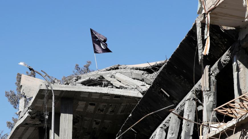 A flag of Islamic State militants is pictured above a destroyed house near the Clock Square in Raqqa, Syria October 18, 2017. Picture taken October 18, 2017.     REUTERS/Erik De Castro - RC159E696010