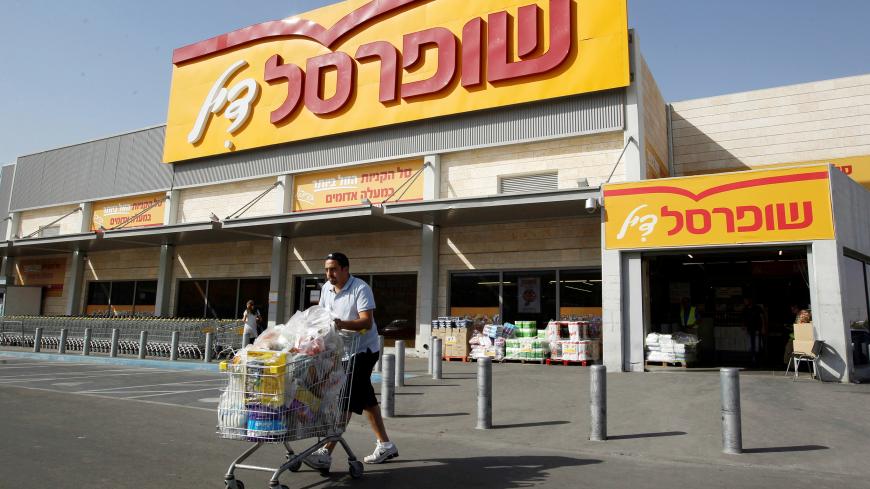 A man pushes a shopping cart outside Shufersal, Israel's largest supermarket chain, in the West Bank Jewish settlement of Mishor Adumim near Jerusalem May 5, 2013. REUTERS/Ammar Awad/File Photo  - S1BEUFEYLVAB