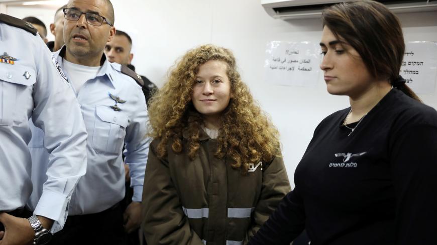 Palestinian teen Ahed Tamimi enters a military courtroom escorted by Israeli security personnel at Ofer Prison, near the West Bank city of Ramallah, January 15, 2018. REUTERS/Ammar Awad - RC1E3EA8C290