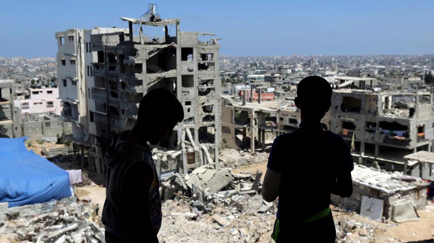Two Palestinian teenagers look at the rubble of destroyed buildings, on June 10, 2015, which were demolished during the 50-day war between Israel and Hamas militants in the summer of 2014, in the Eastern Gaza City Shujaiya neighbourhood. AFP PHOTO / MAHMUD HAMS        (Photo credit should read MAHMUD HAMS/AFP/Getty Images)