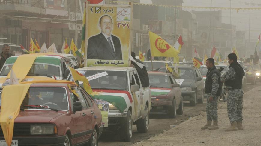 Iraqi policemen look at supporters waving the semi-autonomous region of Kurdistan and Kurdistan Democratic Party (KDP) flags during a sand storm at a rally ahead of March 7 parliamentarian elections in Kirkuk, 250 km (150 miles) north of Baghdad, February 23, 2010. Picture taken February 23, 2010.  REUTERS/Ako Rasheed (IRAQ - Tags: POLITICS ELECTIONS) - GM1E62O14Z601