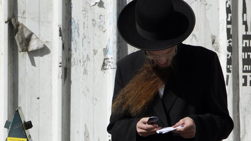 An ultra Orthodox Jewish man uses his cellular phone along a street in Bnei Brak, near Tel Aviv May 3, 2011. Hundreds of thousands of cellphones, popularly dubbed kosher because they block access to services frowned upon by ultra-Orthodox rabbis, have been operating in the Jewish state for more than five years. Last month, Israel's second largest mobile provider, Partner introduced what it hailed as the world's first Yiddish cellphone, manufactured by Alcatel-Lucent. Picture taken May 3, 2011. To match Reut