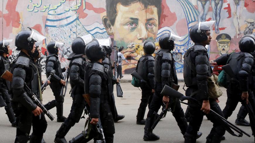 Riot police walk in front of graffiti representing anti-military power and Egypt's unrest, which reads "Glory to the unknown", along Mohamed Mahmoud Street during the third anniversary of violent and deadly clashes near Tahrir Square in Cairo November 19, 2014. Egyptian police arrested 25 individuals after four hundred protestors staged a march through downtown Cairo on the anniversary of deadly clashes with security forces three years ago, the interior ministry said on Wednesday.  REUTERS/Amr Abdallah Dals