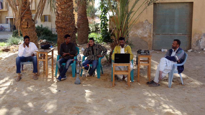 Men smoke and use their mobile phones as they sit at a small cafe in Siwa, November 22, 2014. Residents of Siwa have been hurt by declining tourism in Egypt, which received 9.5 million tourists last year, down from over 14.7 million tourists in 2010, before the uprising that ousted autocrat Hosni Mubarak. Nationwide, the situation is gradually improving and the government says tourism could recover to pre-crisis levels next year if regional turmoil spares Egypt. But Siwa, located just 50 km (30 miles) from 
