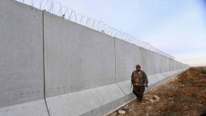 A Kurdish People's Protection Units (YPG) fighter walks near a wall, which activists said was put up by Turkish authorities, on the Syria-Turkish border in the western countryside of Ras al-Ain, Syria January 29, 2016. REUTERS/Rodi Said - GF10000289206