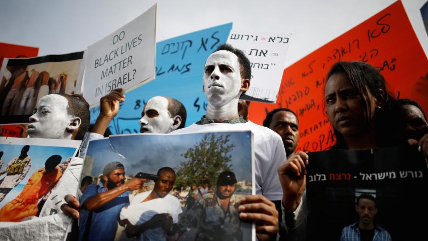 African migrants painted in white hold signs during a protest against the Israeli government's plan to deport part of their community, in front of the Rwandan embassy in Herzliya, Israel February 7, 2018. REUTERS/Amir Cohen - RC1E0E1052F0
