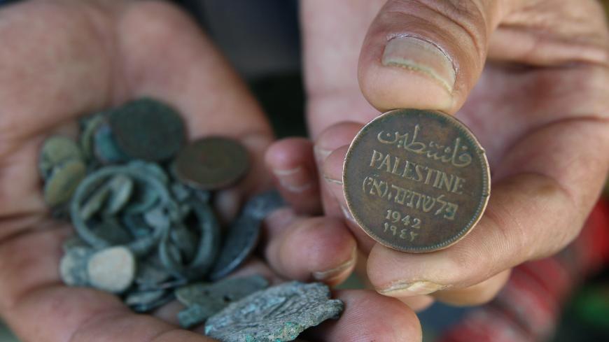 A Palestinian man displays an old Palestinian coin in his shop in the West Bank city of Hebron June 8, 2008. The Palestinian Authority has delayed paying its workers this month after Israel withheld tax funds in anger over Palestinian attempts to block upgraded European Union-Israeli ties, officials said on Sunday. REUTERS/Nayef Hashlamoun (WEST BANK) - GM1E469047K01