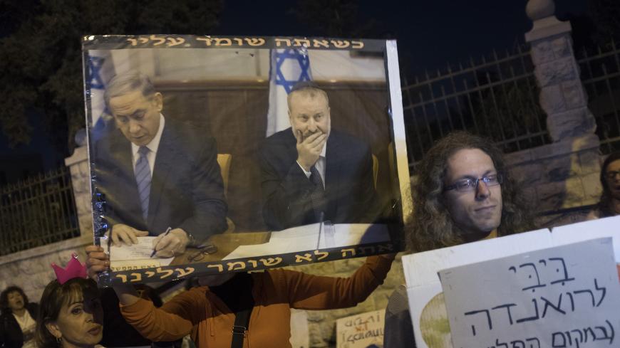 JERUSALEM, ISRAEL - FEBRUARY 14:  (ISRAEL OUT)  An Israeli demonstrator holds a poster with a picture of Israeli Prime Minister Benjamin Netanyahu (L) and Attorney general Avichai Mandelblit during a protest against corruption out side the the Prime Minister's house on February 14, 2018 in Jerusalem, Israel.  A police investigation into Benjamin Netanyahu has concluded  there is enough evidence of bribery, fraud and breach of trust in two separate cases to indict the Israeli Prime Minister.  (Photo by Lior 