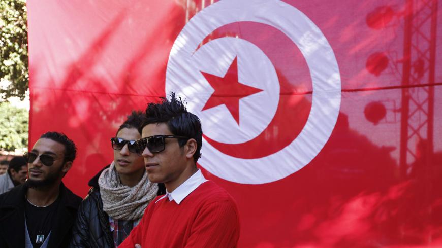 Youths pose for a photo in front a Tunisian flag during celebrations of the second anniversary of the Tunisian revolution at Avenue Habib-Bourguiba in Tunis, January 13, 2013. REUTERS/Anis Mili (TUNISIA - Tags: POLITICS CIVIL UNREST ANNIVERSARY) - GM1E91E09KE01