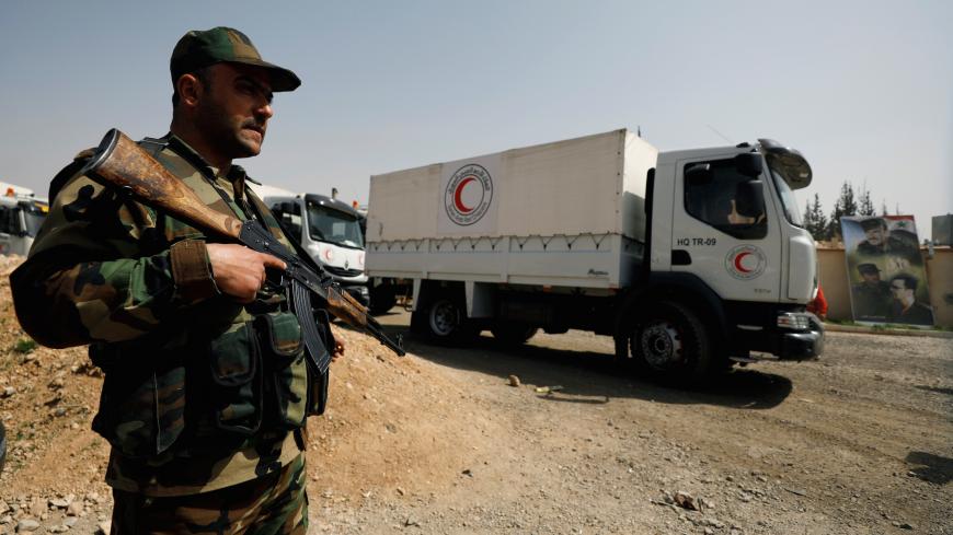 A Syrian army soldier is seen securing Syrian Arab Red Crescent trucks carrying aid at the entrance of Wafideen camp in Damascus, Syria March 5, 2018. REUTERS/Omar Sanadiki - RC12D8D4A5F0