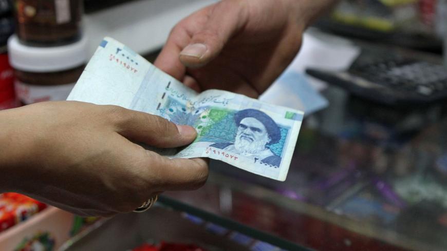 An Iranian woman pays a 20000 rial banknote (around 70 US Cent), bearing a portrait of Iran's late founder of islamic Republic Ayatollah Ruhollah Khomeini, to a grocer in Tehran on September 30, 2012. Iran's currency, the rial has lost over 60 percent of its value since the end of last year, as draconian Western economic sanctions take effect that has spurred already high inflation to even greater heights, with food costs soaring more than 50 percent. AFP PHOTO/ATTA KENARE        (Photo credit should read A