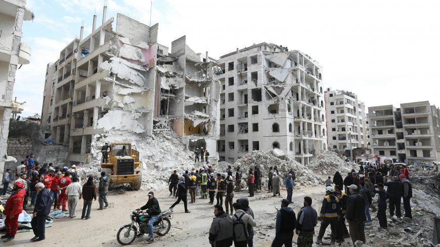 TOPSHOT - Syrian onlookers gather around rescue teams clearing the rubble in the morning of April 10, 2018 at the site of an explosion of unknown origin which wrecked a multi-storey building the previous night in the war-battered country's northwestern city of Idlib.
The cause of the explosion in the jihadist-held city, which killed more than a ten people and wounded 80, according to the Britain-based Syrian Observatory for Human Rights monitoring group, was not immediately clear. / AFP PHOTO / OMAR HAJ KAD