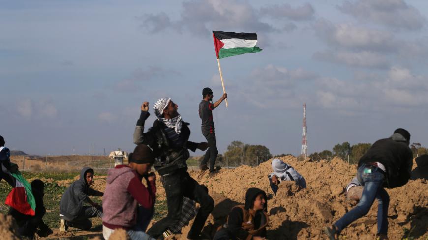 A demonstrator waves a Palestinian flag during clashes with Israeli troops at a protest against U.S. President Donald Trump's decision on Jerusalem, near the border with Israel in the southern Gaza Strip March 16, 2018. REUTERS/Ibraheem Abu Mustafa - RC1D250522B0