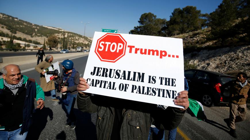 A Palestinian demonstrator holds placard during a protest against a promise by U.S. President-elect Donald Trump to re-locate U.S. embassy to Jerusalem, in the West Bank near Jewish settlement of Maale Adumim, January 20, 2017. REUTERS/Mohamad Torokman - RC1261704EA0
