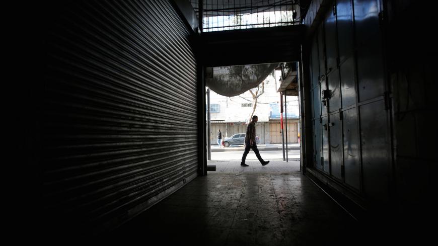 A man passes closed shops as Palestinians call for a general strike, in Hebron, in the occupied West Bank March 31, 2018. REUTERS/Mussa Qawasma - RC1243688B00