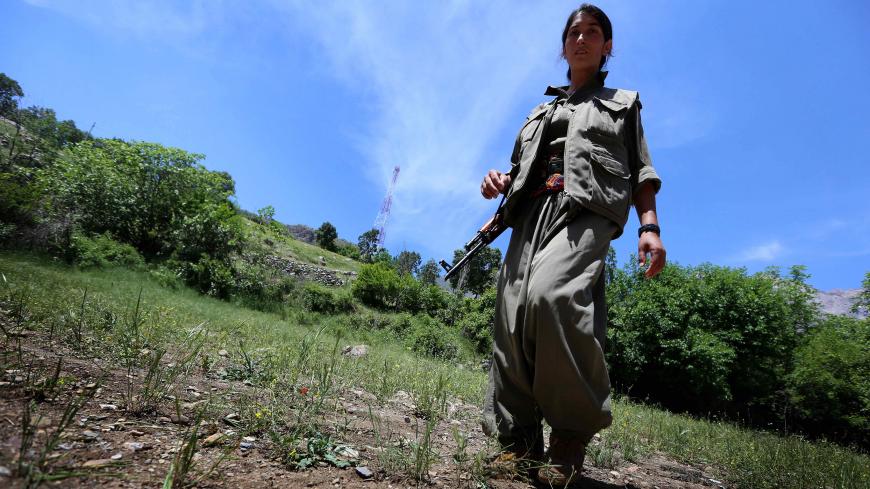 A female member of the anti-Iranian group, the Party of Free Life of Kurdistan (PJAK), carries her weapon as she walks through their base deep in the Qandil mountains of northern Iraq's Kurdish autonomous region, on May 5, 2014. AFP PHOTO/SAFIN HAMED        (Photo credit should read SAFIN HAMED/AFP/Getty Images)