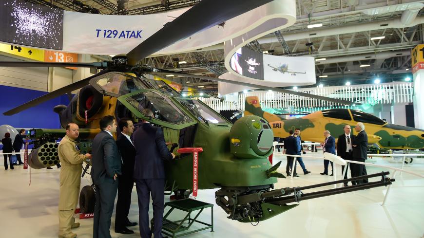 People look at a Turkish attack helicopter "T129 ATAK" on May 9, 2017 during the opening day of the 13th International Defense Industry Fair (IDEF) in Istanbul. / AFP PHOTO / YASIN AKGUL        (Photo credit should read YASIN AKGUL/AFP/Getty Images)