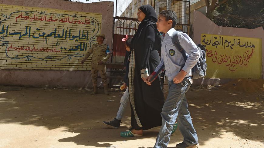An Egyptian woman walks with children in front of the Aziz Al Masri primary school on March 25, 2018 in central Cairo, ahead of the March 26-28 presidential election.
Egypt's military said on March 24 on Twitter that it was making "intensive preparations for the armed forces to secure the presidential election" on March 26-28, after a bombing killed two policemen in Alexandria. / AFP PHOTO / FETHI BELAID / The erroneous mention[s] appearing in the metadata of this photo by FETHI BELAID has been modified in 