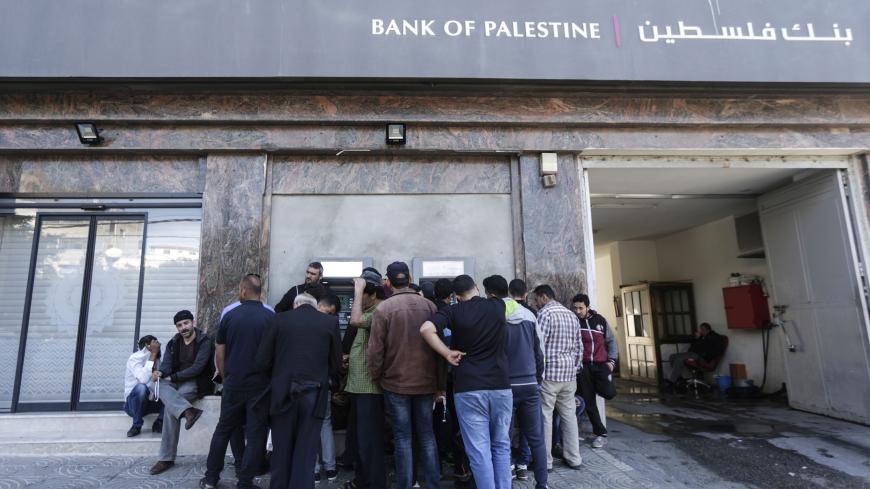 Palestinian employees queue outside a cash machine outside the Bank of Palestine as they wait to withdraw their salaries, in Gaza City on April 9, 2018. (Photo by MAHMUD HAMS / AFP)        (Photo credit should read MAHMUD HAMS/AFP/Getty Images)