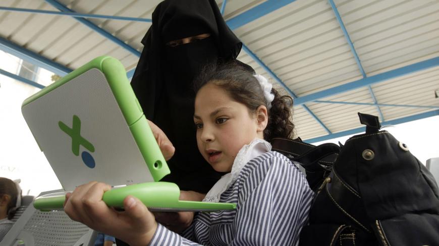 A teacher shows a Palestinian schoolgirl how to use a new laptop at a United Nations school in Rafah refugee camp in the southern Gaza Strip April 29, 2010. The United Nations Relief and Works Agency (UNRWA) launched a campaign to distribute some 200,000 laptops to UNRWA students in the Gaza Strip, an UNRWA official said. REUTERS/Ibraheem Abu Mustafa (GAZA - Tags: POLITICS EDUCATION) - GM1E64T1L8C01