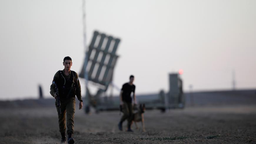 Israeli soldiers walk past an Iron Dome rocket interceptor battery deployed near central Gaza Strip, southern Israel October 31, 2017. REUTERS/Amir Cohen - RC173427FF50