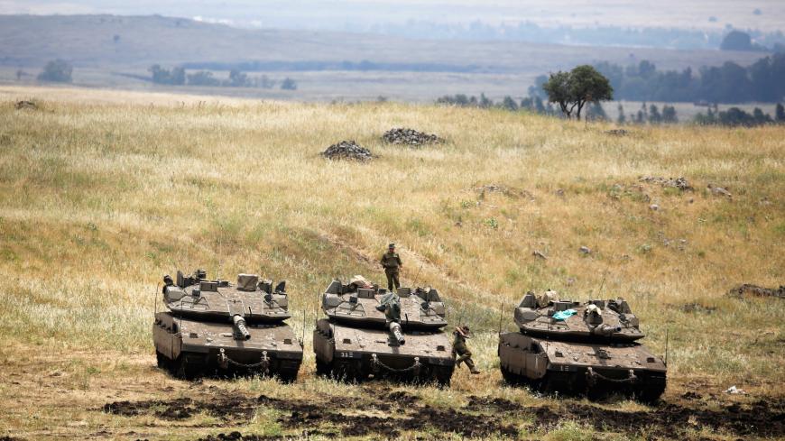 An Israeli soldier stands on a tank as another jumps off it near the Israeli side of the border with Syria in the Israeli-occupied Golan Heights, Israel May 9, 2018. REUTERS/Amir Cohen - RC1520FF8190