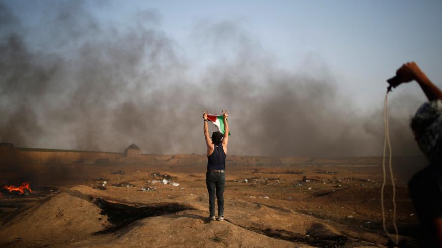 A demonstrator gestures during a protest where Palestinians demand the right to return to their homeland, at the Israel-Gaza border, east of Gaza City May 18, 2018. REUTERS/Mohammed Salem - RC1B62698010