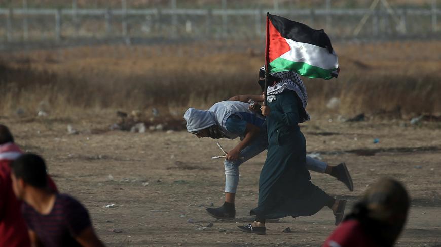 A female demonstrator runs for cover during a protest where Palestinians demand the right to return to their homeland, at the Israel-Gaza border in the southern Gaza Strip May 25, 2018. REUTERS/Ibraheem Abu Mustafa - RC1190AE6040