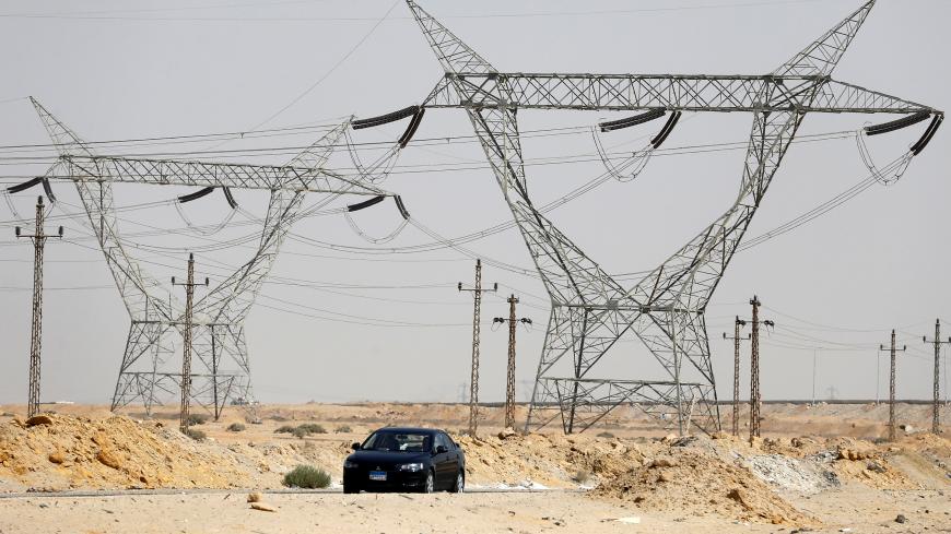 A car passes power lines connecting pylons of high-tension electricity at the highway in Cairo, Egypt August 14, 2017. REUTERS/Amr Abdallah Dalsh - RC122337A6E0