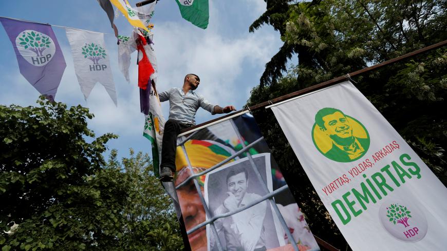 A supporter of the pro-Kurdish Peoples' Democratic Party (HDP) hangs posters of Selahattin Demirtas, the party's jailed former co-leader and the candidate for the upcoming presidential election, during a gathering in Istanbul, Turkey May 4, 2018. REUTERS/Murad Sezer - RC18E770B250