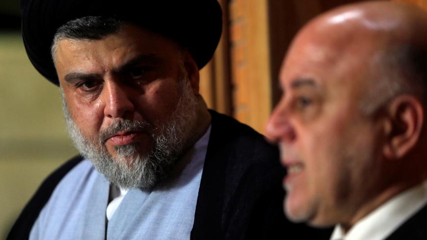 Iraqi Shi'ite cleric Moqtada al-Sadr, who's bloc came first, looks at Iraqi Prime Minister Haider al-Abadi, who's political bloc came third in a May parliamentary election, during a news conference in Najaf, Iraq June 23, 2018. REUTERS/Alaa al-Marjani - RC1D0E2C2810