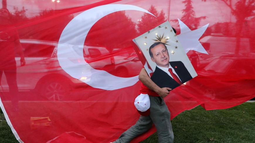 A supporters of Turkish President Tayyip Erdogan holds his picture in front of a Turkish flag, in front of Turkey's ruling AK Party (AKP) headquarters in Istanbul,Turkey, June 24, 2018. REUTERS/Goran Tomasevic      TPX IMAGES OF THE DAY - RC1D72DCC500
