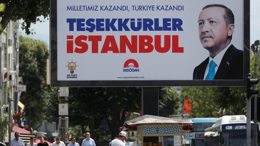 People walk past a poster for Turkey's President Tayyip Erdogan in Istanbul, Turkey, June 25, 2018. The poster reads: "Our people won, Turkey won, Thank you istanbul". REUTERS/Osman Orsal - RC19D0C486D0