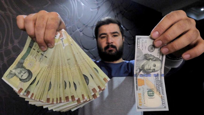A money changer poses for the camera with a U.S  hundred dollar bill (R) and the amount being given when converting it into Iranian rials (L), at a currency exchange shop in Tehran's business district, Iran, January 20, 2016. REUTERS/Raheb Homavandi/TIMA  ATTENTION EDITORS - THIS IMAGE WAS PROVIDED BY A THIRD PARTY. FOR EDITORIAL USE ONLY. - GF20000100969