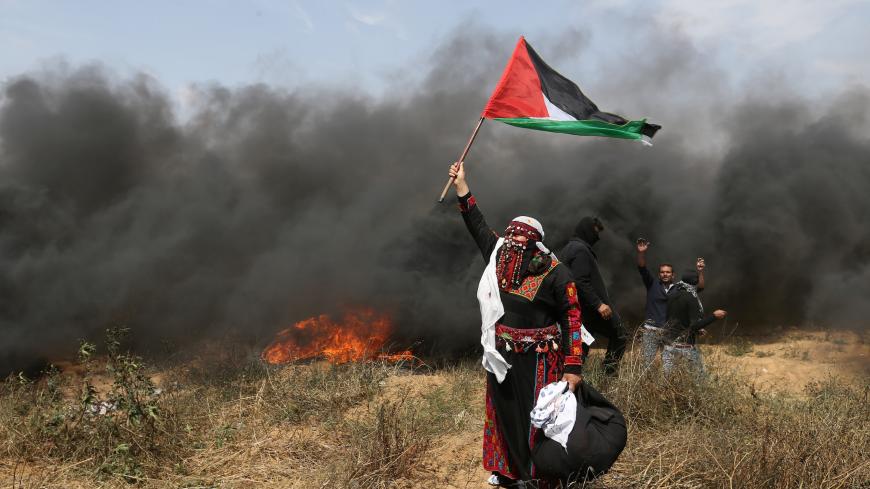 A woman demonstrator holds a Palestinian flag during clashes with Israeli troops at a protest where Palestinians demand the right to return to their homeland, at the Israel-Gaza border in the southern Gaza Strip, April 27, 2018. REUTERS/Ibraheem Abu Mustafa - RC1C308400C0