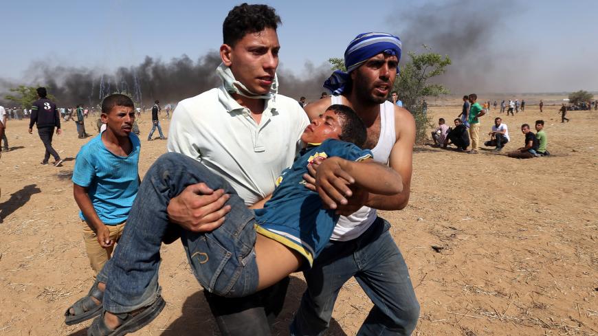 A wounded Palestinian boy is evacuated during a protest marking al-Quds Day, (Jerusalem Day), at the Israel-Gaza border in the southern Gaza Strip June 8, 2018. REUTERS/Ibraheem Abu Mustafa - RC1DC5C1B3A0
