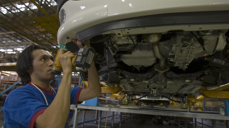 A worker installs a bumper on a car at the Iran Khodro automobile manufacturing plant, west of Tehran January 28, 2009. Iran Khodro is the Middle East's largest carmaker. Picture taken January 28, 2009.  REUTERS/Caren Firouz (IRAN) - GM1E51T1GH901